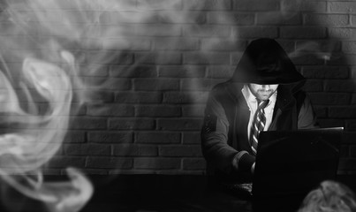 Hacker in black mask and hood at the table