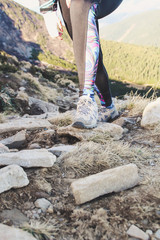 Tourist in the mountains. Tourist shoes on a stone. Woman rises to the mountain. Hiking trips.