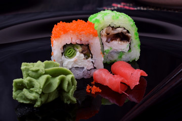 Fresh sushi rolls with cream cheese, rice, caviar and seafood against the black background. Asian cuisine meal
