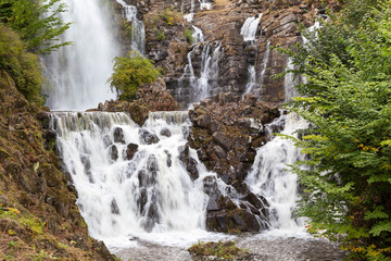 Beautiful waterfall with stone formation and plants on a mountain in the rainforest.