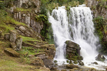 Beautiful waterfall with stone formation and plants on a mountain in the rainforest.
