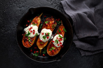 Grilled eggplants with yogurt sauce, pomegranate seeds, parsley and green onion in cast iron vintage pan.
