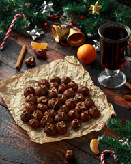 Roasted chestnuts served on crumpled paper with Christmas decoration, gifts, green tree branch. wooden rustic table