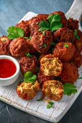 Indian Pakora snack spicy onion, red pepper with chilli sauce on white wooden board