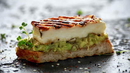 Avocado and grilled haloumi cheese toast with nigella and sesame seeds. healthy breakfast