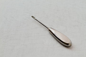Metal old rare dental instrument for removing teeth on white gauze background. Black and white photo.