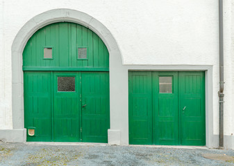 house front with white plaster stone walls and bright green doors