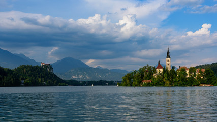 Iconic landscape view of beautiful St. Marys Church of Assumption on small island,lake Bled in Slovenia .Bled Castle on background. Summer scene travel Slovenia concept. Tourist popular attraction