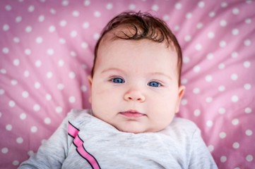 Closeup image of the face of the deep blue eyes baby girl looking at the camera portrait. Happy...