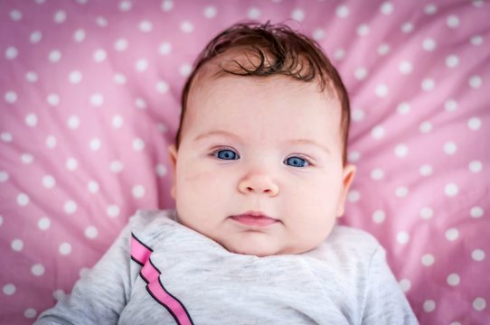 Closeup image of the face of the deep blue eyes baby girl looking at the camera portrait. Happy childhood concept image.