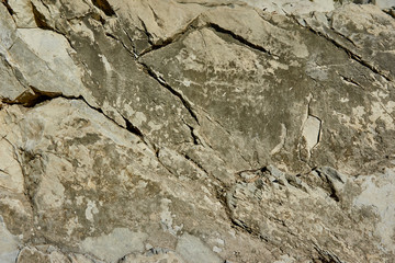 Mountain stone with a natural texture as a design concept. Cracks created by nature on the surface of the stone with a natural color scheme, create a natural textured background. Texture for design .