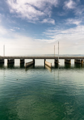 vertical view of a concrete bridge over water with a train line and road running parallel and a boat and ship passageway below