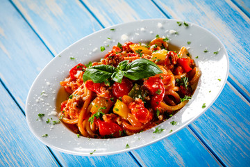 Pasta with meat, tomato sauce and vegetables on wooden table