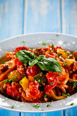Pasta with meat, tomato sauce and vegetables on wooden table