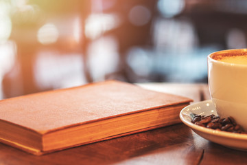 One cup of coffee, coffee beans and book on a wooden board