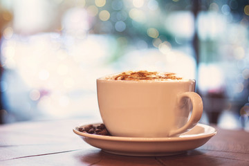 One cup of milk coffee and coffee beans on a wooden board