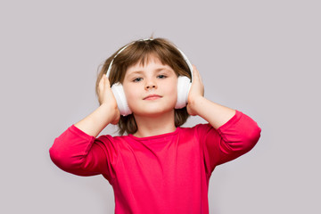 Happy smiling child enjoys listens to music in headphones over white