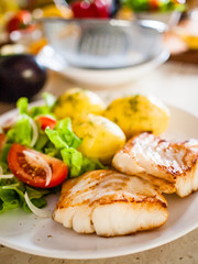 Fried fish with potatoes on white plate