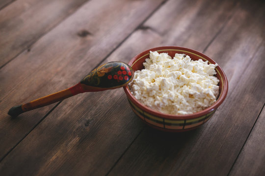 Bowl with cottage cheese on a natural wooden table