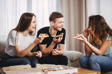 party, leisure, people eating, friendship, food delivery. cheerful friends hang out in living room enjoy pizza and laughing at home party
