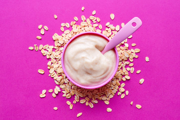 Bowl of baby porridge on pink, from above