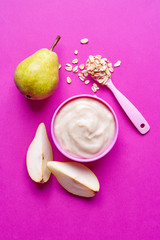 Bowl of baby porridge on pink, from above
