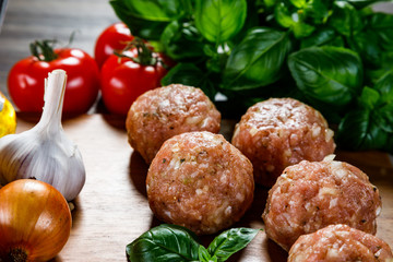 Raw meatballs on cutting board on wooden background