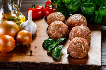 Raw meatballs on cutting board on wooden background
