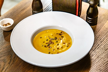 Pumpkin cream soup poured into a large white plate