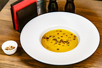Pumpkin cream soup poured into a large white plate