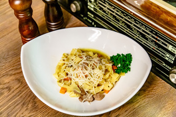 Fettuccine pasta with clear sauce with meat lies in a white plate