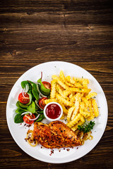 Grilled chicken fillet with french fries on wooden table
