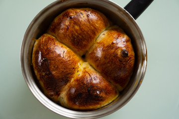 Homemade raisin danish style bread in a stainless steel pan on a glass table