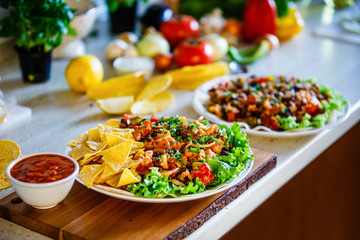 Grilled meat with nachos and vegetables on wooden background