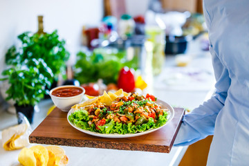Grilled meat with nachos and vegetables on wooden background