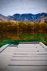 Natural landscape view of the autumn red-orange color forest with the reflection on the lake surface