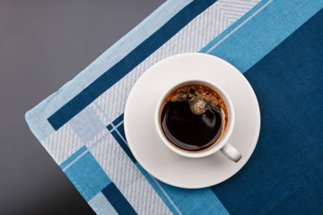 Top view of a black coffee cup on fabric background.