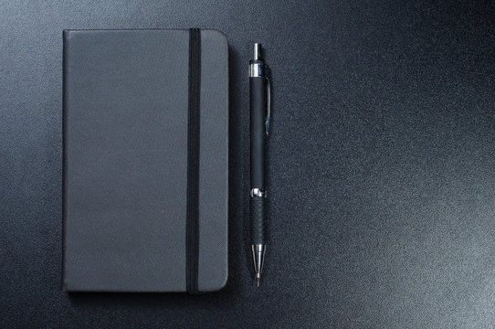  38/5000 chernyy bloknot s ruchkoy na chernom fone black notebook with pen on black background