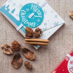 Christmas composition. Christmas red and white gifts boxes and cinnamon sticks on canvas background. Flat lay