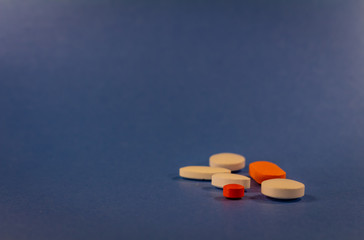 Pills of various colors on a neutral blue background.
