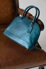 women leather bag on a brown chair without logo, advertising shooting bags, presentation bags, leather handbag.