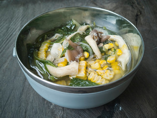 Selective focus the healthy Vegetable Soup consists of mushroom, corn and spinach on the top of wooden table.