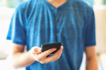 Young man using his smartphone in a bright interior room