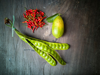 Selective focus of Parkia Speciosa or Petai in Malaysian language, red chillies and lemon lime on...