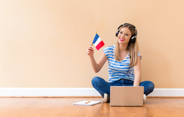 Young woman with French flag using a laptop computer against a big interior wall