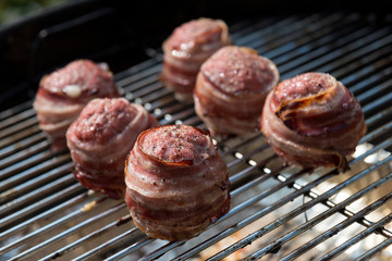 Cooking meatballs covered with bacon on the grill