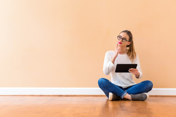 Young woman with a tablet computer against a big interior wall