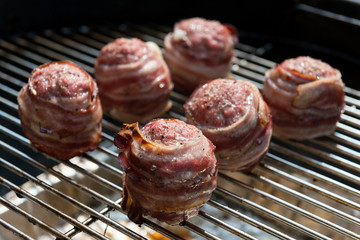 Cooking meatballs covered with bacon on the grill
