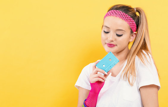 Woman in 1980's fashion holding a cassette tape on a yellow background