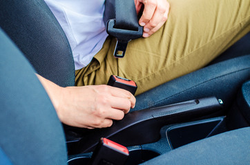 Female driver fastening seat belt in the car before driving